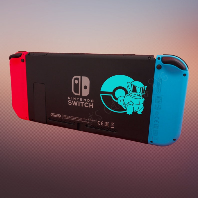 May include: A black Nintendo Switch console with a blue and red Joy-Con controller. The console has a sticker of a blue Pokemon character with a Pokeball on a blue background.