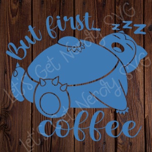 Może przedstawiać: Niebieski projekt graficzny ze śpiącym stworzeniem z kresk&oacute;wek i tekstem "But first, coffee" na drewnianym tle.