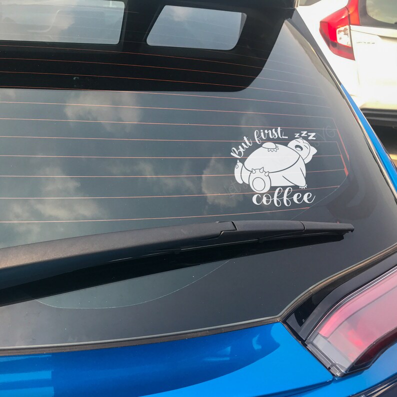 Może przedstawiać: Niebieski samoch&oacute;d z białym naklejką na tylnej szybie. Naklejka przedstawia śpiącego kreskowego niedźwiedzia i tekst "but first...zzz coffee".