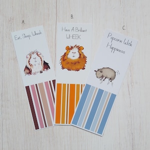 May include: Three colorful bookmarks featuring illustrations of guinea pigs with text that reads "Eat, Sleep, Wheek", "Have A Brilliant WHEEK", and "Popcorn With Happiness".