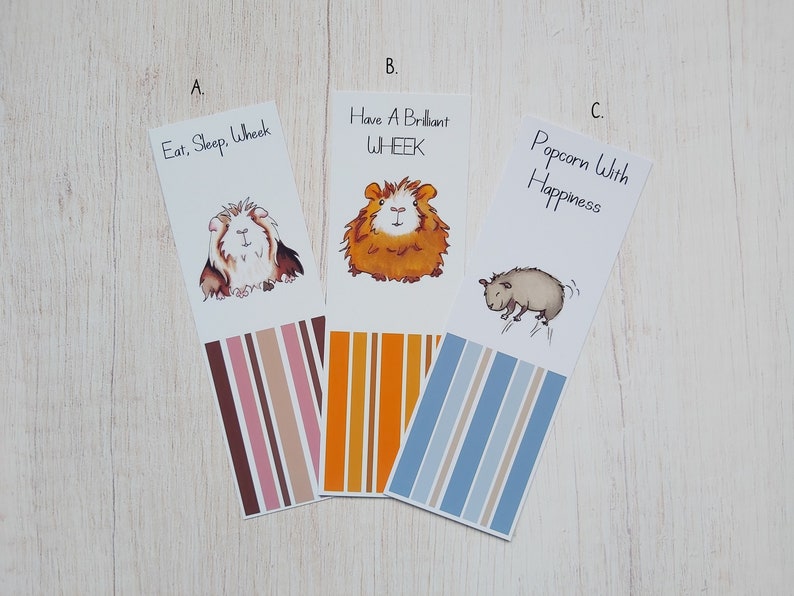 May include: Three colorful bookmarks featuring illustrations of guinea pigs with text that reads "Eat, Sleep, Wheek", "Have A Brilliant WHEEK", and "Popcorn With Happiness".