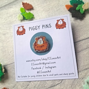 May include: A card with the text "PIGGY PINS" and contact information for the shop CCoxonArt. The card features a cartoon image of a brown and white guinea pig.
