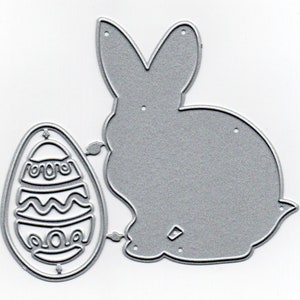 May include: A silver metal die cut of an Easter bunny and an Easter egg. The bunny is sitting with its ears up and the egg is decorated with a wavy pattern.