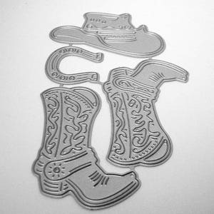 May include: A die-cut metal set featuring cowboy-themed shapes. The set includes a cowboy hat, a horseshoe, and two cowboy boots. The boots have decorative patterns and a spur detail. The shapes are silver and designed for crafting.