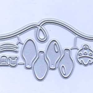 May include: A silver metal die cut with a design of a string of lights with various shapes, including stars, bows, and bells. The die cut is perfect for creating festive cards and scrapbook pages.