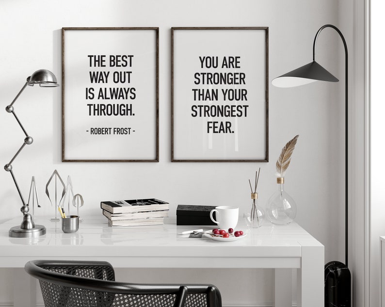 K&ouml;nnte beinhalten: Zwei gerahmte inspirierende Zitate an einer wei&szlig;en Wand. Das Zitat links lautet "Der beste Weg nach drau&szlig;en ist immer durch. - Robert Frost." Das Zitat rechts lautet "Du bist st&auml;rker als deine gr&ouml;&szlig;te Angst."