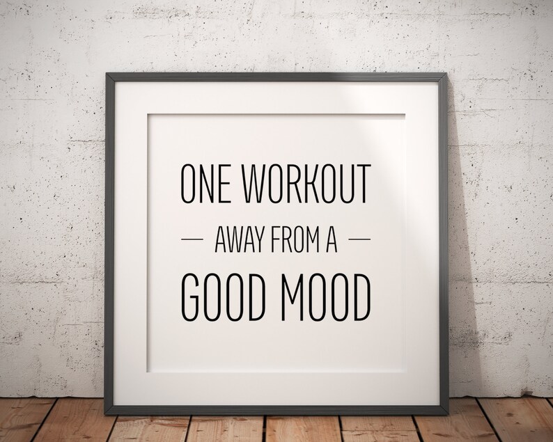 May include: A framed motivational quote that reads "One workout away from a good mood". The frame is black and the background is a white brick wall.