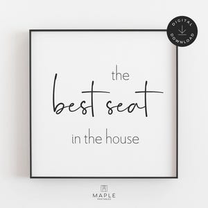 May include: A framed print with a white background and black text that reads "the best seat in the house." The print has a black border and a digital download icon in the upper right corner.