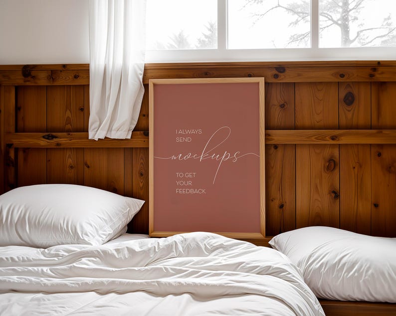 May include: A framed poster with a light brown wood frame and a red background. The poster says "I always send mockups to get your feedback". The poster is hanging on a wooden wall above a white bed with white pillows.