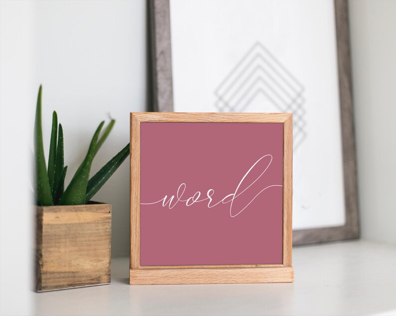 May include: A wooden framed sign with a pink background and the word "word" written in white cursive script.