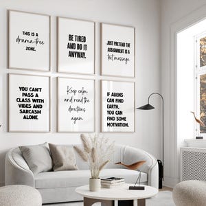 May include: A living room scene featuring six framed art prints with black text on a white background. The prints display motivational and humorous quotes. A white sofa, round coffee table, and decorative items complete the modern interior design.