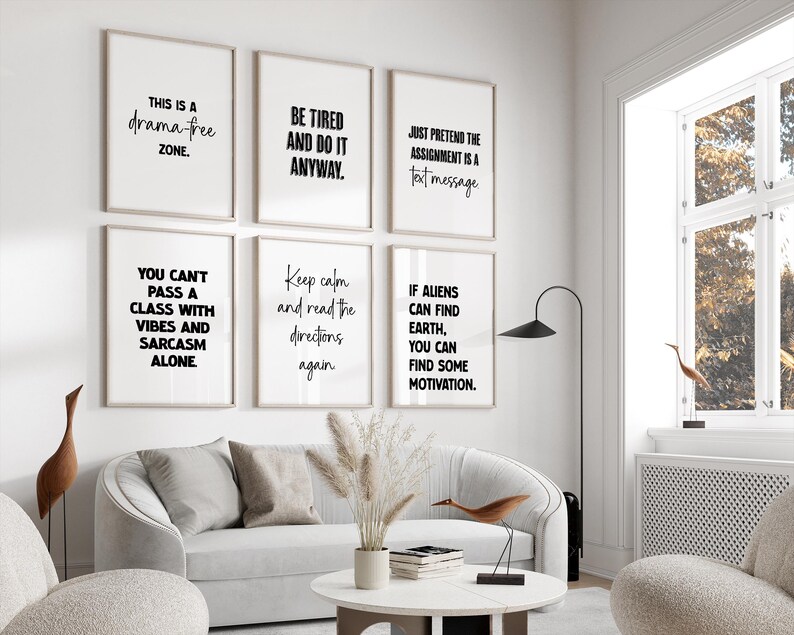 May include: A living room scene featuring six framed art prints with black text on a white background. The prints display motivational and humorous quotes. A white sofa, round coffee table, and decorative items complete the modern interior design.
