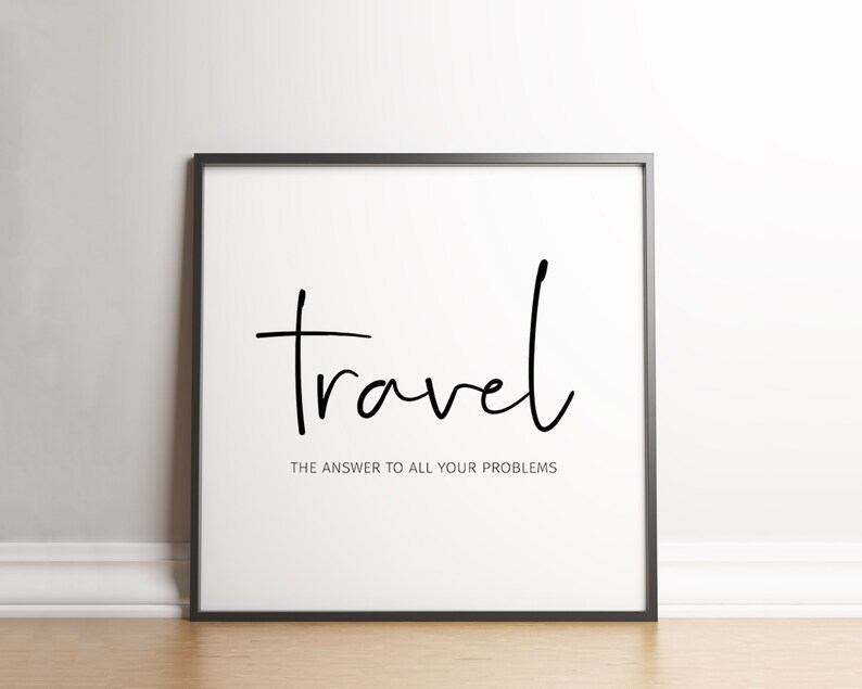 May include: A framed print with the word "travel" in a handwritten style, with the phrase "THE ANSWER TO ALL YOUR PROBLEMS" below it. The text is black on a white background, framed in a black frame.