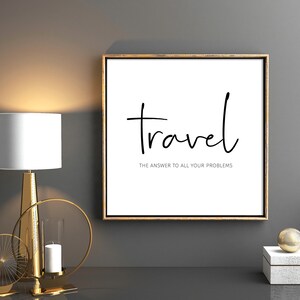 May include: A framed print with the word "Travel" in a handwritten font, with the text "the answer to all your problems" below it. The print is displayed on a gray wall, next to a gold lamp and decorative objects.