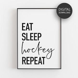 Op de afbeelding: Een rechthoekige zwarte lijst met een witte print met de zwarte tekst EAT SLEEP hockey REPEAT. Een cirkelvormige zwarte badge in de rechterbovenhoek bevat de witte tekst DIGITAL DOWNLOAD. Het ontwerp bevat een combinatie van verschillende lettertypes.