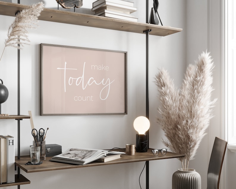 Może przedstawiać: Wydruk w ramie z r&oacute;żowym tłem i białym tekstem, kt&oacute;ry brzmi "make today count", wiszący na ścianie nad drewnianym biurkiem z lampą, wazą z suszoną trawą pampasową i książką.