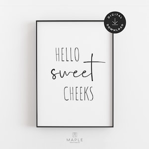 以下が含まれることがあります： 「HELLO sweet CHEEKS」の文字が黒い筆記体とブロック体で書かれたフレームプリント。プリントは黒いフレームに入っており、背景は白です。デジタルダウンロードアイコンが右上隅にあります。