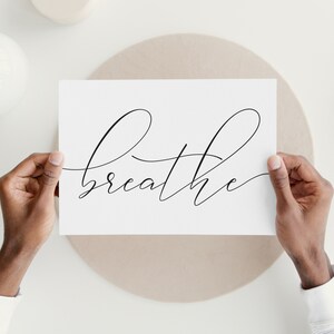 May include: A white card with the word "breathe" written in black cursive script.