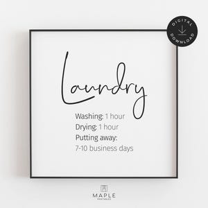 This image shows a framed square poster with the word Laundry" in a cursive font. Below, it lists laundry times: "washing: 1 hour, drying: 1 hour, putting away: 7-10 business days." The print features black text on a clean white background and is displayed in a black frame. A small circle in the corner says “Digital Download.”