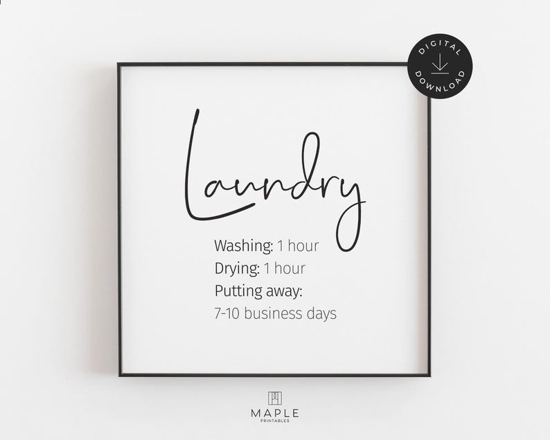 This image shows a framed square poster with the word Laundry" in a cursive font. Below, it lists laundry times: "washing: 1 hour, drying: 1 hour, putting away: 7-10 business days." The print features black text on a clean white background and is displayed in a black frame. A small circle in the corner says “Digital Download.”