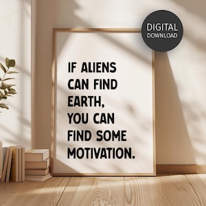 Op de afbeelding: Een ingelijste print met de tekst "IF ALIENS CAN FIND EARTH, YOU CAN FIND SOME MOTIVATION." De print staat in een licht houten frame en heeft een digitaal downloadlabel. De print leunt tegen een muur met boeken en een plant op de achtergrond.