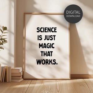May include: A framed print with the text "SCIENCE IS JUST MAGIC THAT WORKS" in bold black letters. The print is in a light wood frame and is labeled "DIGITAL DOWNLOAD" in a black circle. The print is leaning against a wall.