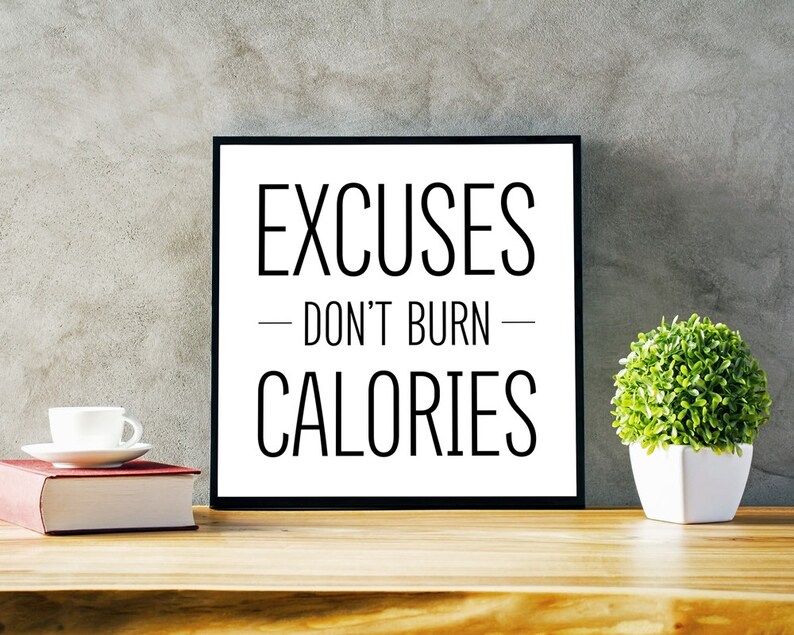 May include: Black and white motivational quote on a framed poster that reads "Excuses - Don't Burn - Calories". The poster is sitting on a wooden table with a white coffee cup and a book.