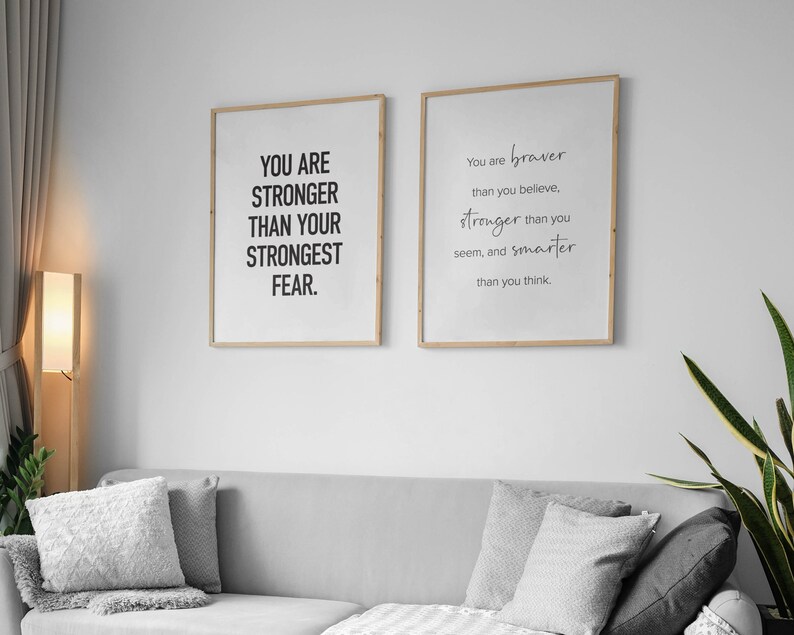 K&ouml;nnte beinhalten: Zwei gerahmte Motivationsposter mit wei&szlig;em Hintergrund und schwarzem Text. Das linke Poster sagt "You are stronger than your strongest fear." Das rechte Poster sagt "You are braver than you believe, stronger than you seem, and smarter than you think."