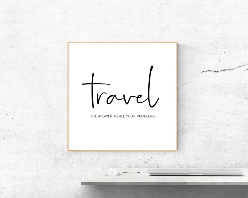 May include: A framed print with the word "travel" in black script, with the phrase "the answer to all your problems" below it. The print is in a light wood frame, set against a white wall.