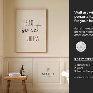 May include: A framed wall art print with the text "Hello Sweet Cheeks" in a bathroom setting. The print is in a light-colored frame. A small wooden stool holds a towel, soap dispenser, and a small glass. The wall art is for a home or office bathroom.