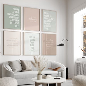 May include: Six motivational posters with inspirational quotes in white text on a light background. The posters are hung on a white wall in a living room setting.