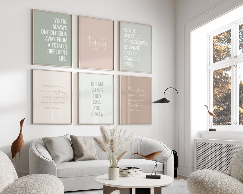 May include: Six motivational posters with inspirational quotes in white text on a light background. The posters are hung on a white wall in a living room setting.