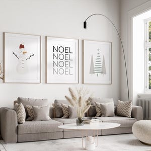 Pu&ograve; includere: Tre stampe incorniciate con un tema invernale. La prima stampa presenta un pupazzo di neve con un cappello rosso. La seconda stampa ha la parola "NOEL" ripetuta quattro volte. La terza stampa mostra un albero di Natale stilizzato.