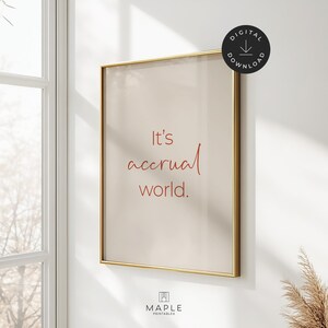 以下が含まれることがあります： 赤い筆記体で「It's accrual world」と書かれた額入りのプリント。プリントはベージュの背景と金のフレームです。デジタルダウンロードアイコンは右上にあります。