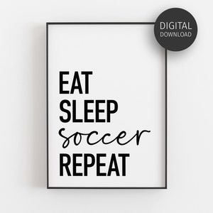 May include: A rectangular black frame containing a white print with the black text EAT SLEEP soccer REPEAT. A circular black badge in the top right corner displays the white text DIGITAL DOWNLOAD. The design features a mix of sans-serif and script fonts.