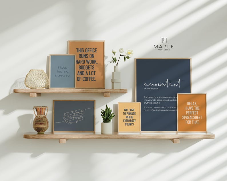 Puede incluir: Una exhibici&oacute;n de impresiones art&iacute;sticas enmarcadas con citas motivacionales y definiciones. Las impresiones son de varios tama&ntilde;os y colores, incluyendo azul, naranja y amarillo, y est&aacute;n dispuestas en estantes de madera. El texto incluye frases como "accountant" y "Welcome to Finance."