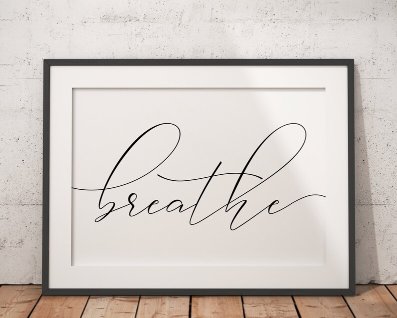May include: A black framed print with a white background and the word "breathe" written in a cursive font.