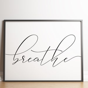 May include: A black and white printable wall art print with the word "breathe" written in cursive script.