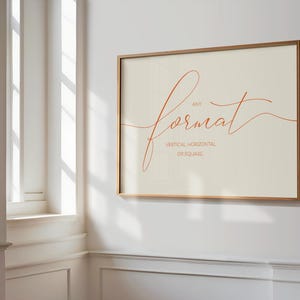 May include: A framed print with a light beige background and a handwritten orange script that says "any format" with the words "vertical, horizontal, or square" written below in smaller font.