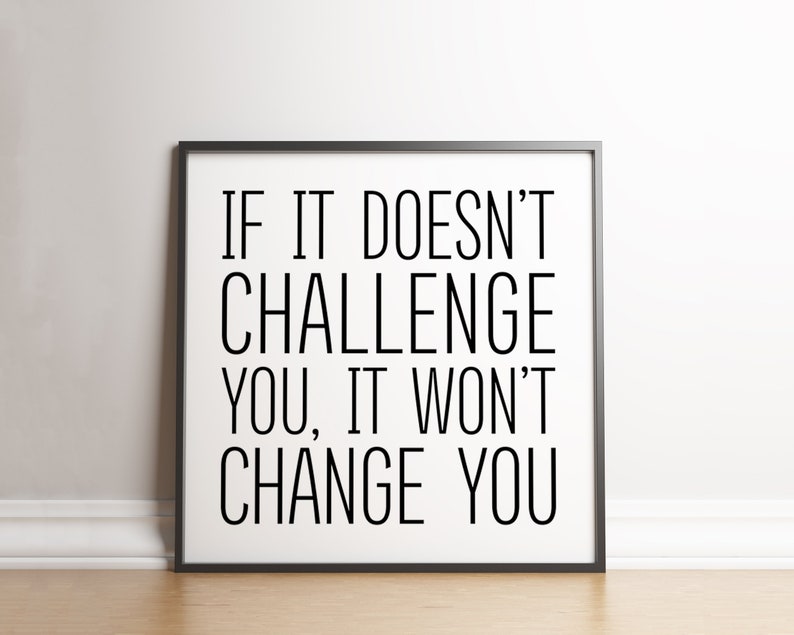 May include: Black and white motivational quote in a black frame on a white wall. The quote reads "If it doesn't challenge you, it won't change you."