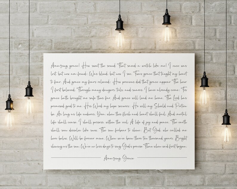 K&ouml;nnte beinhalten: Ein wei&szlig;er Leinwanddruck mit schwarzem Text, der die Worte des Kirchenliedes "Amazing Grace" zeigt. Der Text ist mittig auf der Leinwand platziert und von einem wei&szlig;en Rand umgeben.