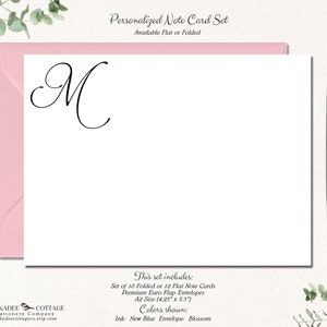 May include: A set of personalized note cards with the letter "M" in a cursive font. The cards are available in flat or folded styles and come with envelopes. The text on the card reads "This set includes: Set of 10 Folded or 12 Flat Note Cards Premium Euro Flap Envelopes A2 Size (4.25"x5.57 Colors shown: Ink: New Blue Envelope: Blossom"
