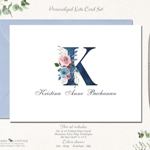May include: Personalized note card set with a navy blue letter K decorated with pink and blue watercolor flowers. The name Kristina Anne Buchanan is written in navy blue cursive script below the letter. The set includes 10 folded note cards and envelopes, measuring 4.25 inches by 5.5 inches.