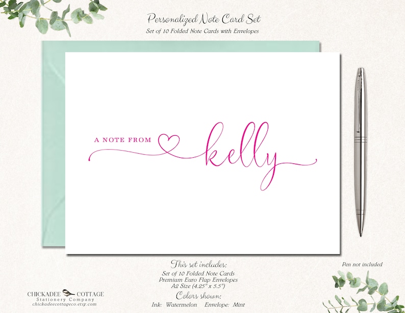 May include: A personalized note card set with a white card and mint envelope. The card features the text "A NOTE FROM" and the name "kelly" in a watermelon pink script font. A silver pen rests beside the card.