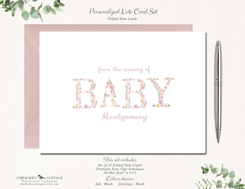 May include: A set of 10 folded note cards with blush colored envelopes. The cards feature a floral design spelling out the word "BABY" with the name "Montgomery" below. The text "from the nursery of" is above the floral design. The cards are A2 size (4.25" x 5.5").
