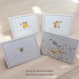 May include: Set of 16 folded note cards with envelopes featuring bee-themed illustrations. The cards are white with black borders and feature a variety of bee-related designs, including a jar of honey, a beehive, and a bee in a field of flowers. The cards are printed with the name "Mary Montgomery" in black.