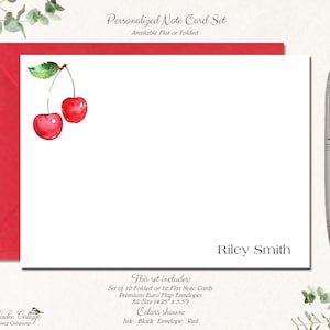 May include: A set of personalized note cards with a watercolor illustration of two red cherries. The cards are available in flat or folded styles and come with envelopes. The text on the card reads "Riley Smith".