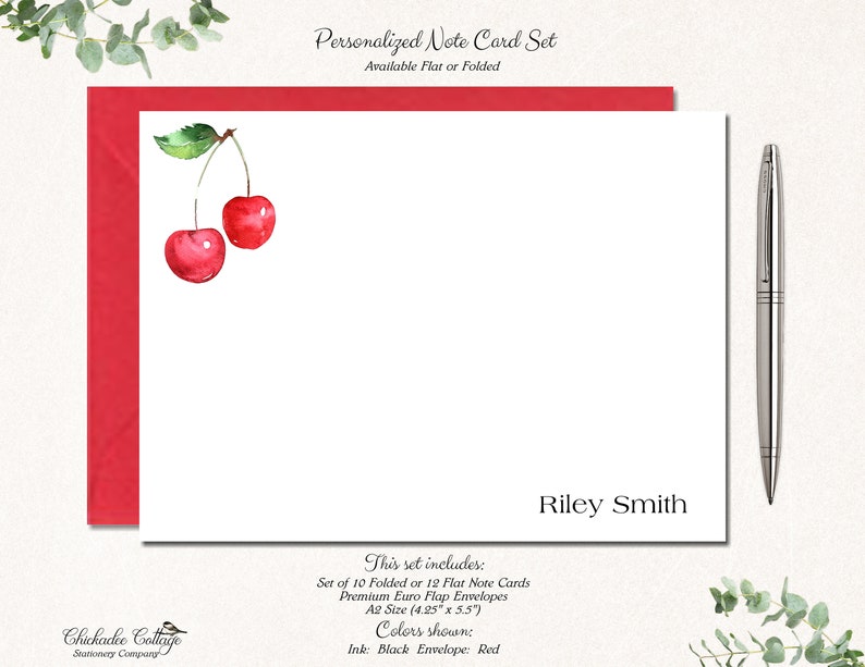 May include: A set of personalized note cards with a watercolor illustration of two red cherries. The cards are available in flat or folded styles and come with envelopes. The text on the card reads "Riley Smith".