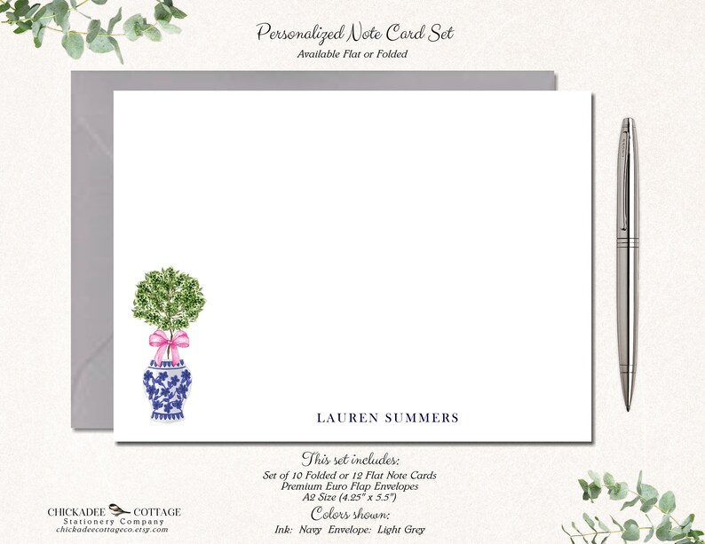 May include: Personalized note card set with a watercolor illustration of a potted tree with a pink ribbon. The card set includes 10 folded or 12 flat note cards and premium euro flap envelopes. The cards are A2 size (4.25" x 5.5"). The ink color is navy and the envelope color is light grey. The text on the card reads "LAUREN SUMMERS".