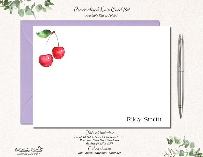 May include: Personalized note card set with a watercolor illustration of two red cherries. The set includes 10 folded or 12 flat note cards and premium Euro flap envelopes. The cards are A2 size (4.25" x 5.5"). The ink color is black and the envelope color is lavender. The name "Riley Smith" is printed on the card.